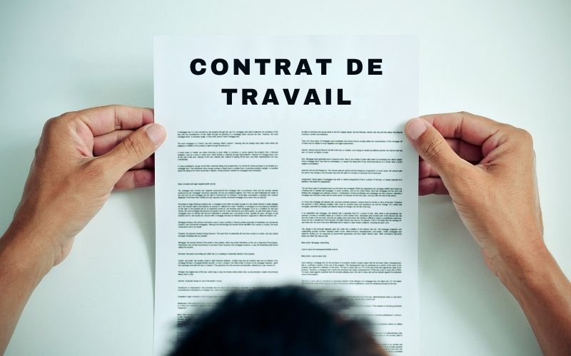 Contrat de travail tenu entre les mains.