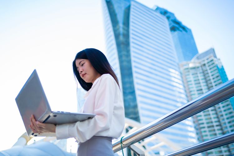 Professionnelle utilisant un ordinateur portable dans un quartier d’affaires moderne.