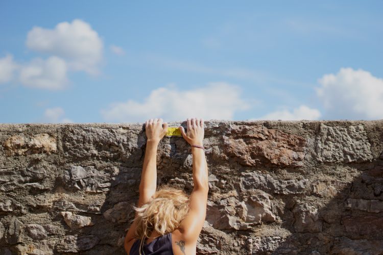 Person climbing a wall to represent challenges in the Cambodian market.