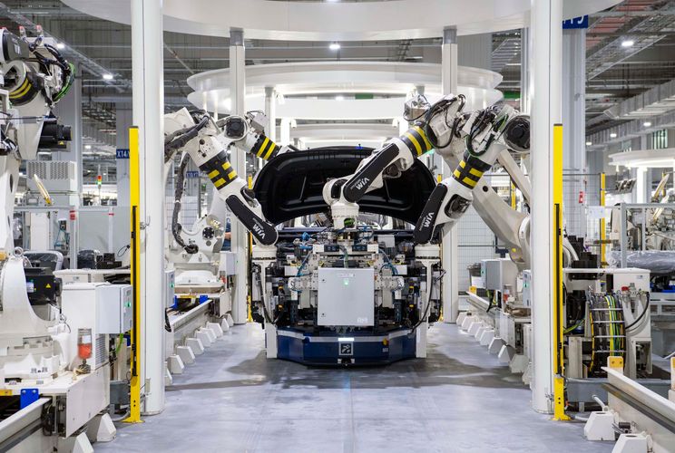 Vehicle assembled by robotic arms on an automated production line.